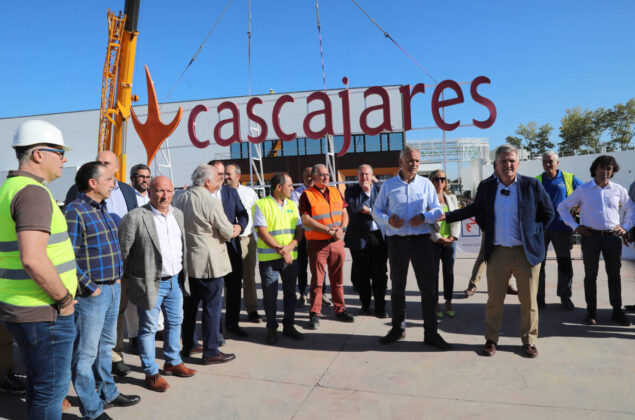 Responsables y trabajadores de Cascajares y de las empresas constructoras junto al cartel de Cascajares que sobrevivió al incendio y que se ha vuelto a recolocar en las nuevas instalaciones. / Brágimo (ICAL)