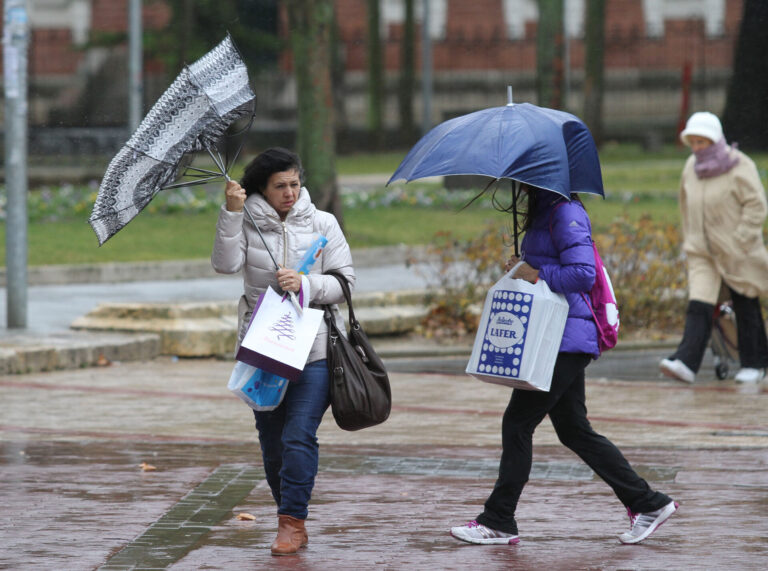 Temporal de viento y lluvia en Palencia. En la imagen unas mujeres sortean el agua y el viento en la plaza de la Pio XII de Palencia. / Brágimo (ICAL)
