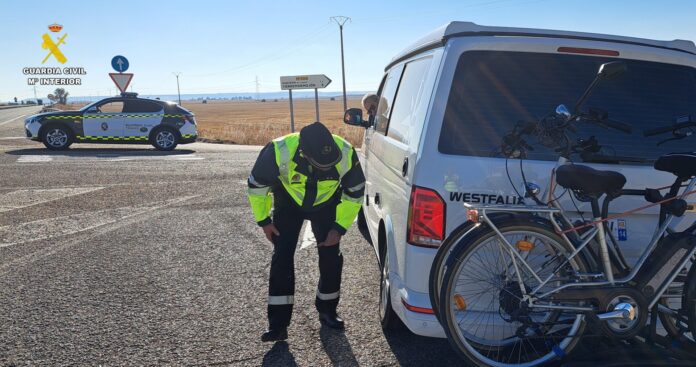 Un agente de tráfico controla el estado del neumático de una furgocamper francesa en la N-610.