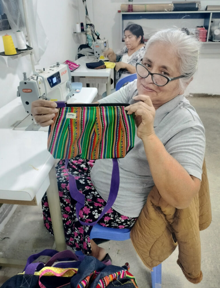 Un mujer peruana muestra unos de los bolsos elaborados en un taller de Paita, región de Piura de Perú y que se comercializan en la tienda Vida propia de Guardo (Palencia)