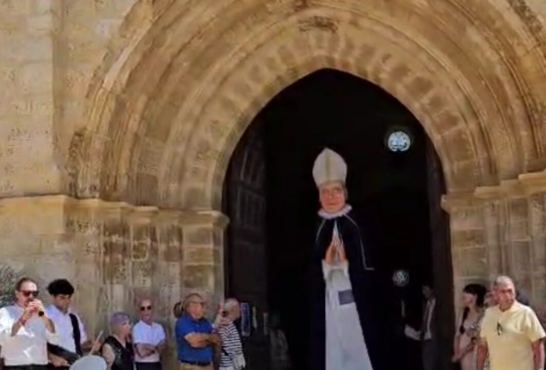 El abad Reinoso, representado como figura gigante, sale de la iglesia de Husillos para iniciar el pasacalles