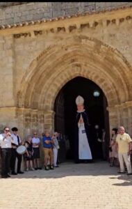 El abad Reinoso, representado como figura gigante, sale de la iglesia de Husillos para iniciar el pasacalles