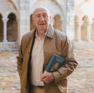 José María Pérez Peridis sosteniendo su libro en un monasterio restaurado