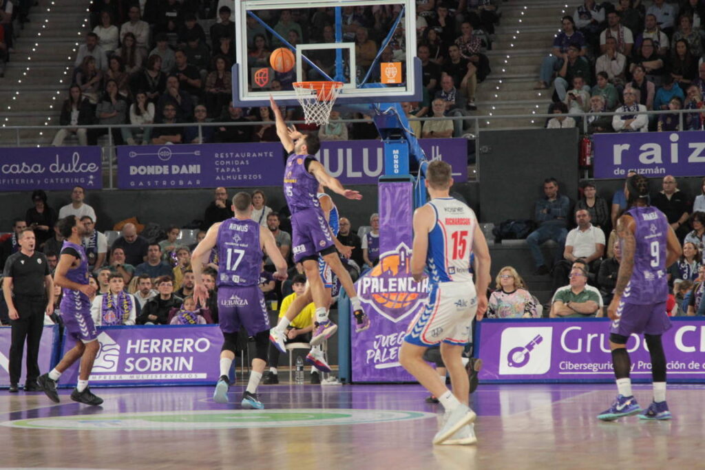 Jugador del equipo de Palencia saltando para encestar en un partido de baloncesto.