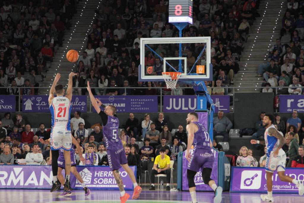 Jugador lanzando el balón en un partido de baloncesto entre Palencia y Alicante.