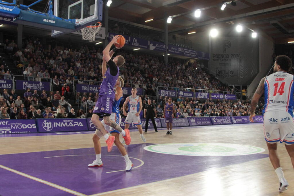 Jugador del equipo de Palencia lanzando a canasta durante un partido de baloncesto