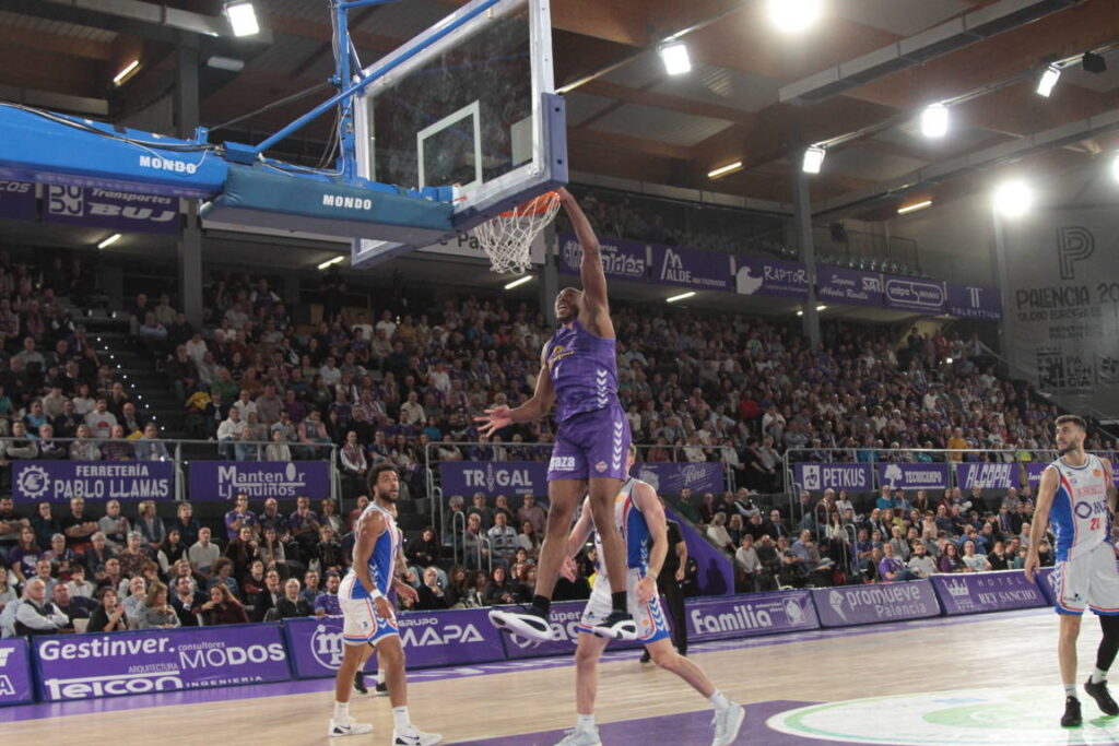 Jugador realizando un mate durante un partido de baloncesto en Palencia.