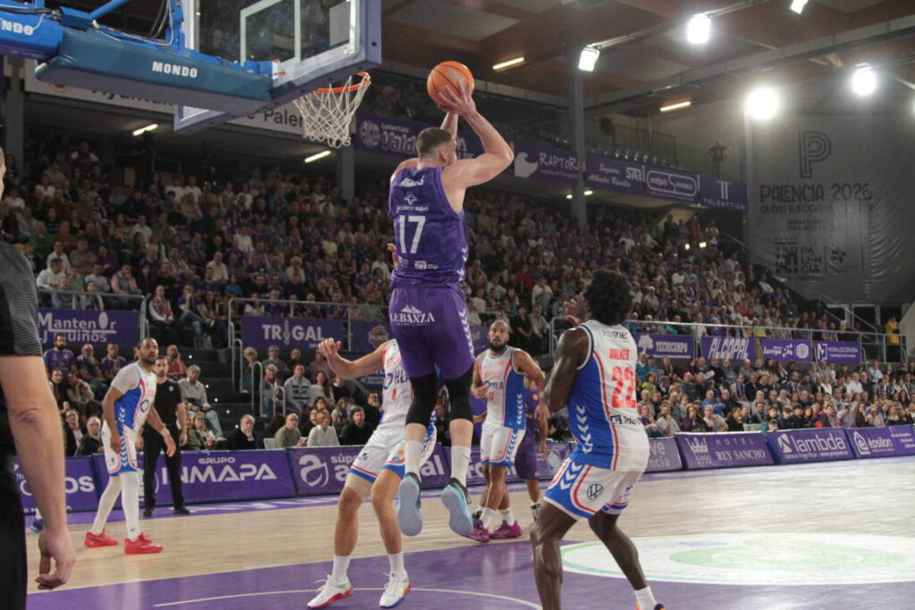 Jugador del Palencia saltando para encestar durante un partido de baloncesto.