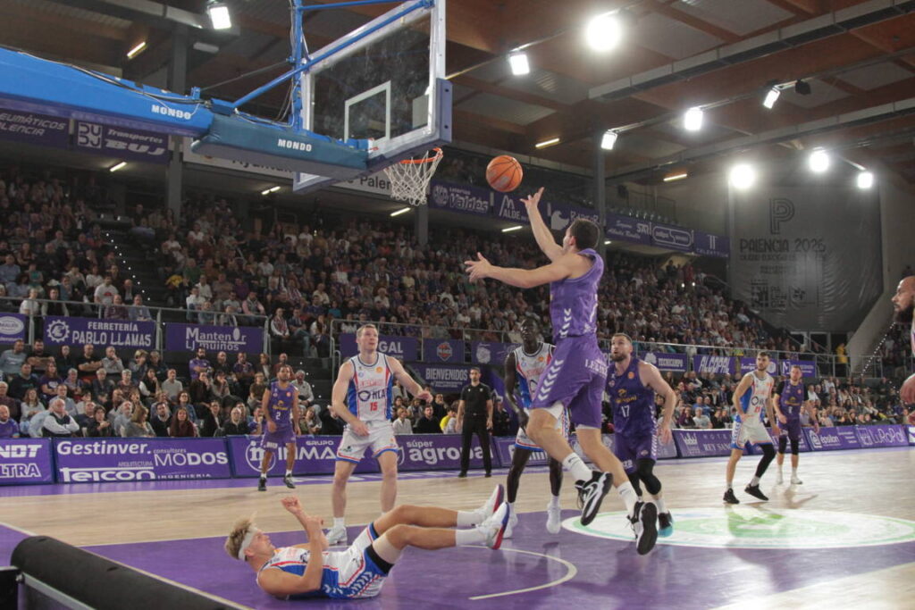 Jugador lanzando el balón durante un partido de baloncesto en Palencia.