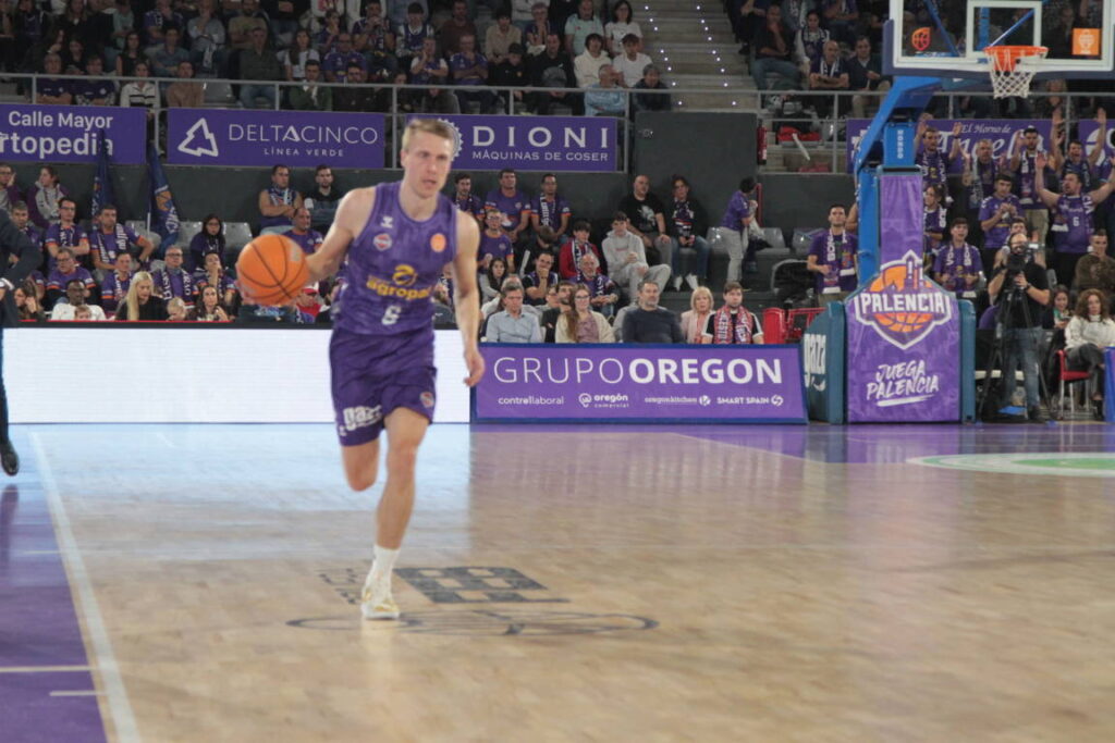 Jugador del equipo de baloncesto de Palencia corriendo con el balón en la cancha