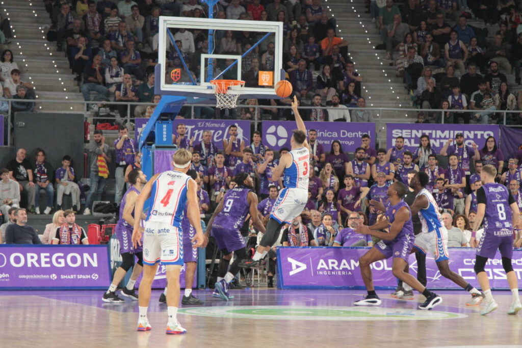 Jugador lanzando a canasta durante un partido de baloncesto