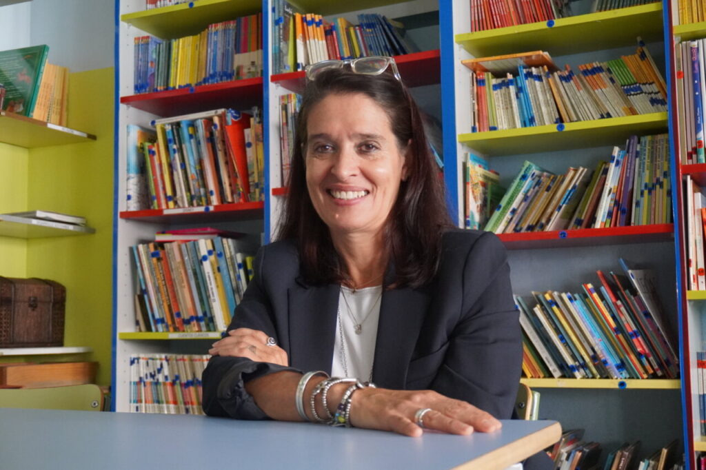 Mar Romera sonriendo en una biblioteca con estanterías llenas de libros