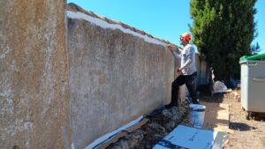 Álvaro pintando la pared interior del cementerio de Husillos con maestría.