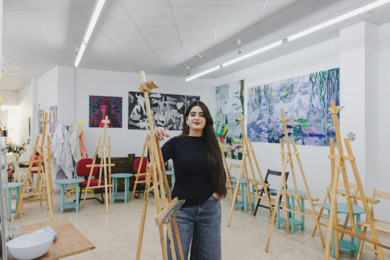 Joven pintora en su estudio rodeada de caballetes y obras de arte