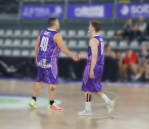 Jugadores de baloncesto saludándose en la cancha durante un partido
