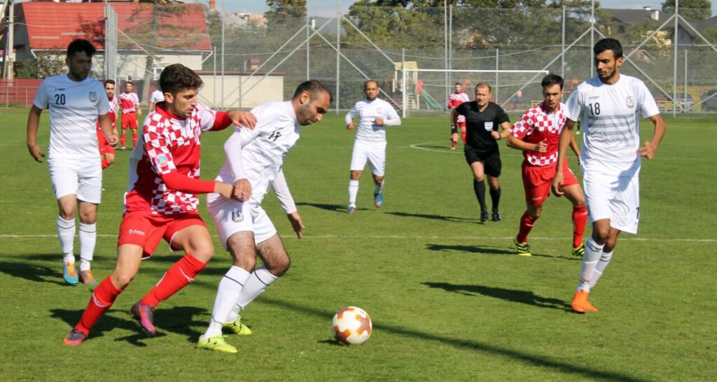 Jugadores compitiendo en un partido de fútbol en un campo verde.