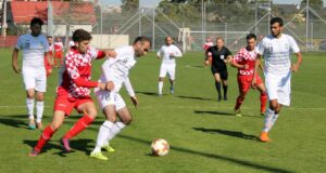 Jugadores compitiendo en un partido de fútbol en un campo verde.