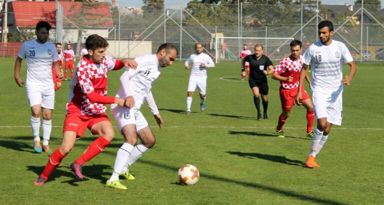 Jugadores compitiendo en un partido de fútbol en un campo verde.