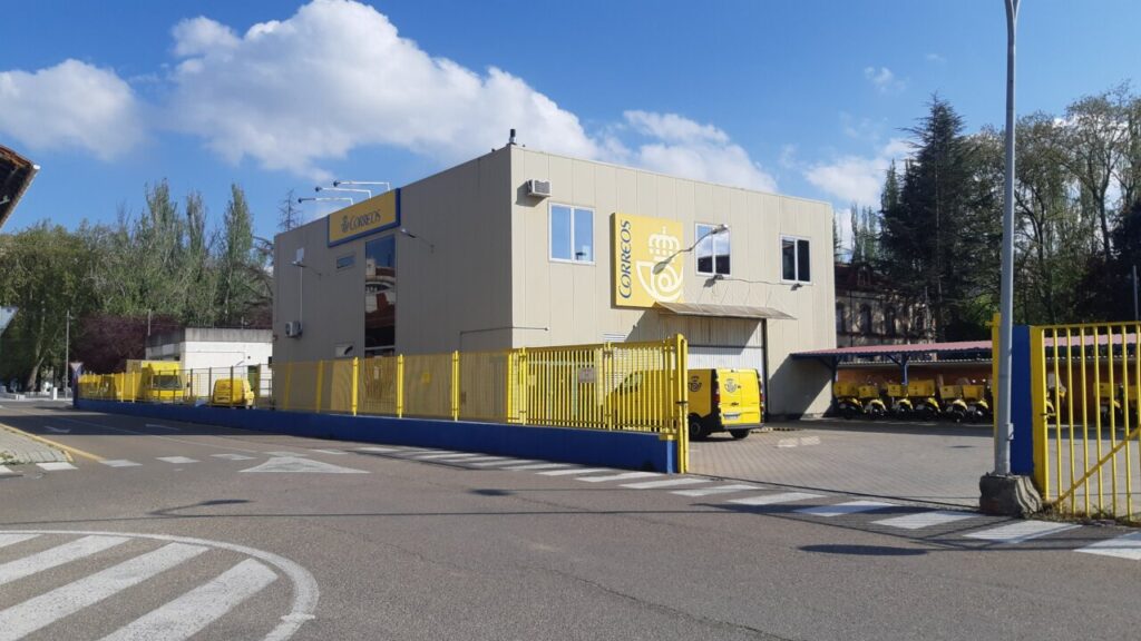 Edificio de Correos en Palencia con vehículos amarillos estacionados