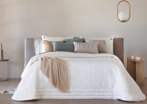 Edredón blanco sobre una cama con cojines decorativos