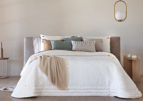 Edredón blanco sobre una cama con cojines decorativos