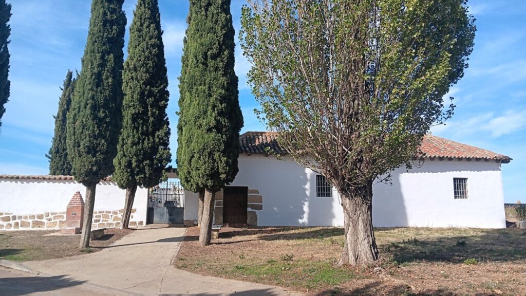 Fachada exterior embellecida del cementerio de Husillos con árboles alrededor.