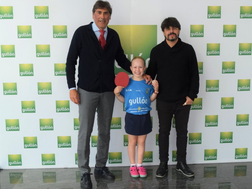 Nerea Hidalgo, campeona de tenis de mesa, con dos hombres en evento de apoyo.