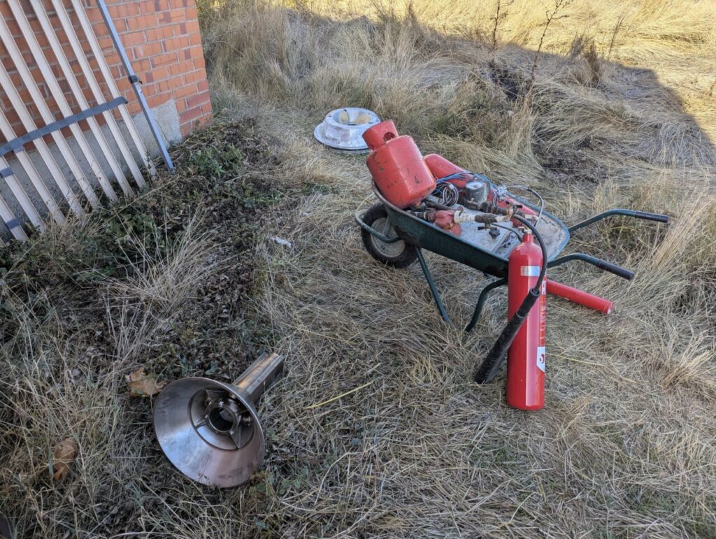 Materiales abandonados cerca de una quesería con hierba seca