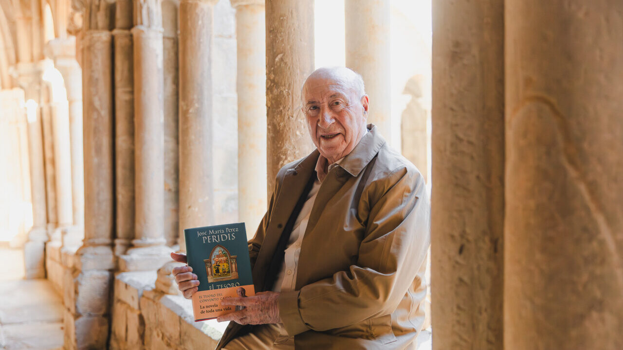 José María Pérez Peridis sosteniendo su libro en un monasterio