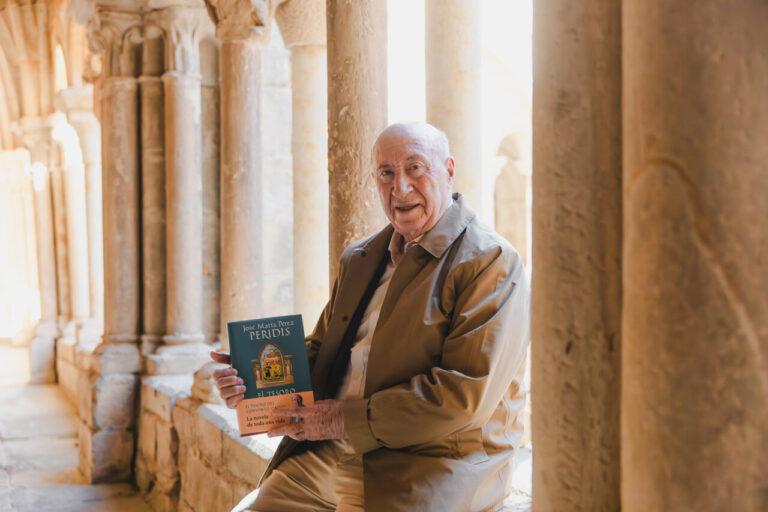 José María Pérez Peridis sosteniendo su libro en un monasterio