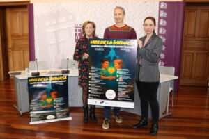 Tres personas sosteniendo un cartel sobre el Mes de la Infancia en Palencia