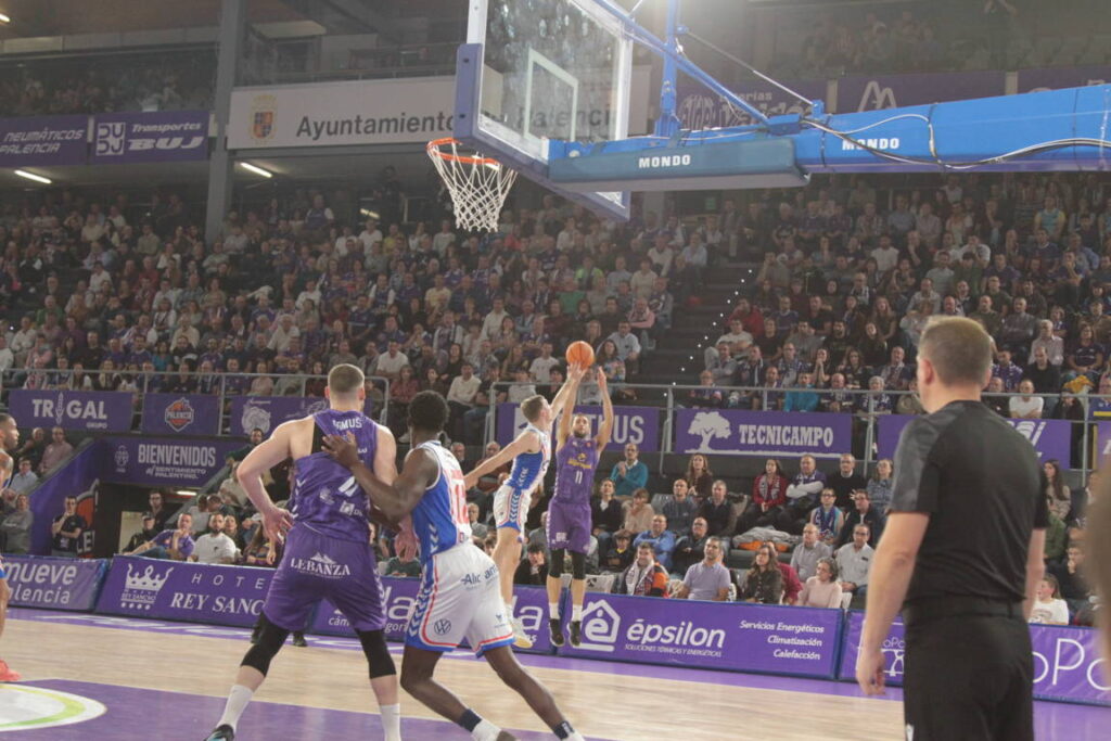 Jugador del equipo de Palencia lanzando a canasta durante un partido de baloncesto