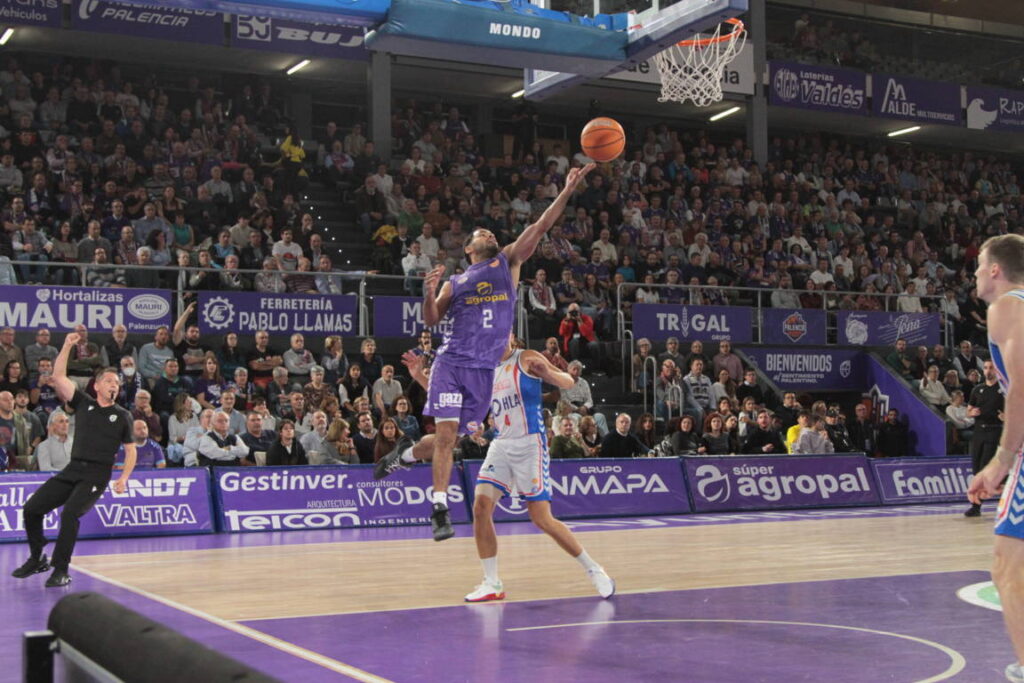 Jugador saltando para encestar en un partido de baloncesto