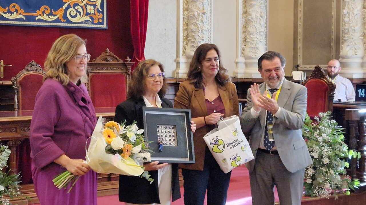 Entrega de un premio en una ceremonia con flores y un cuadro