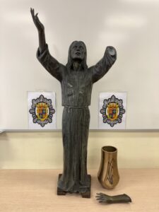 Escultura de un Cristo con los brazos levantados en un fondo neutro