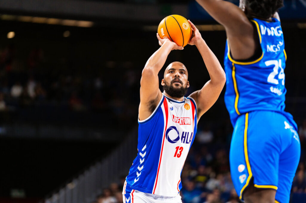 Jugador lanzando a canasta en un partido de baloncesto