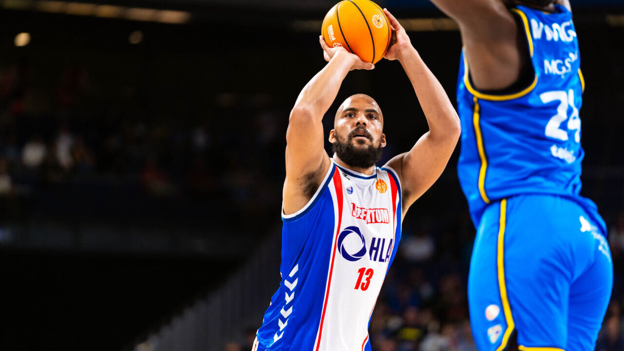 Jugador lanzando a canasta en un partido de baloncesto