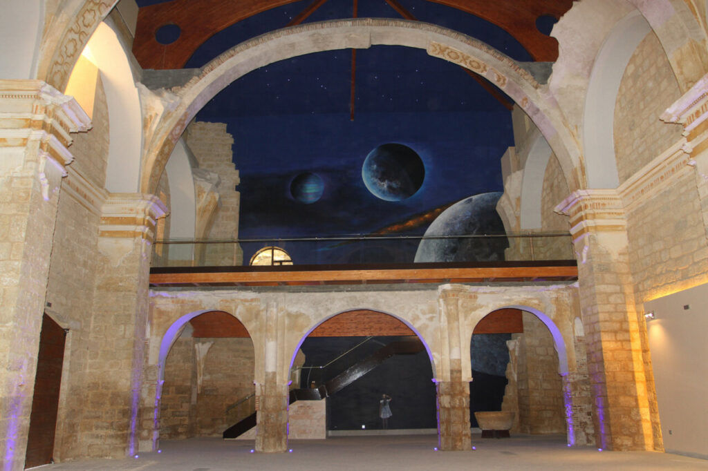 Interior de un edificio histórico con mural de planetas