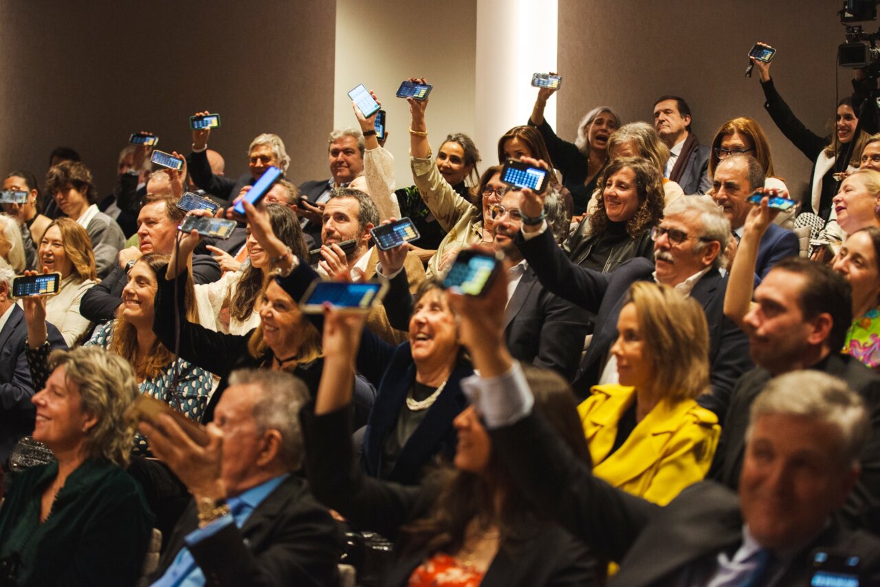 Asistentes levantando sus teléfonos durante la subasta benéfica de capones