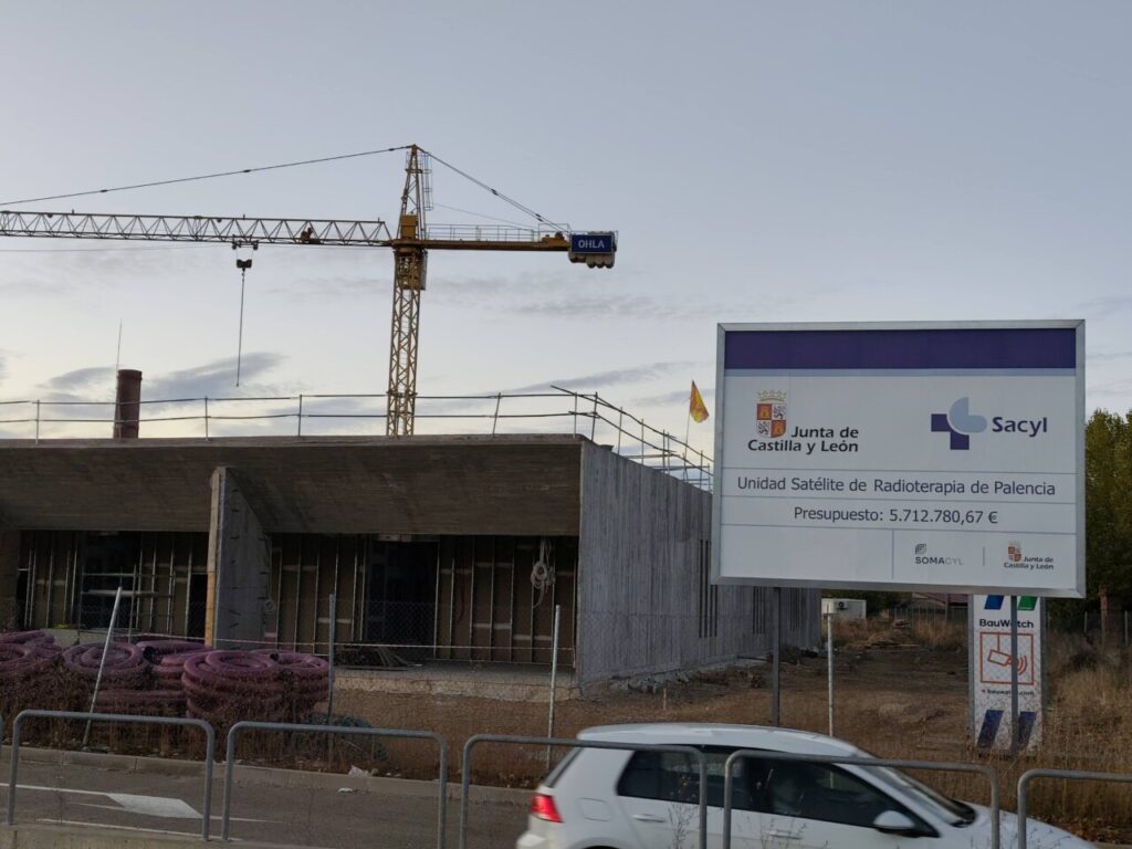 Construcción de la Unidad Satélite de Radioterapia en Palencia con grúa y cartel informativo.