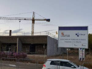 Construcción de la Unidad Satélite de Radioterapia en Palencia con grúa y cartel informativo.