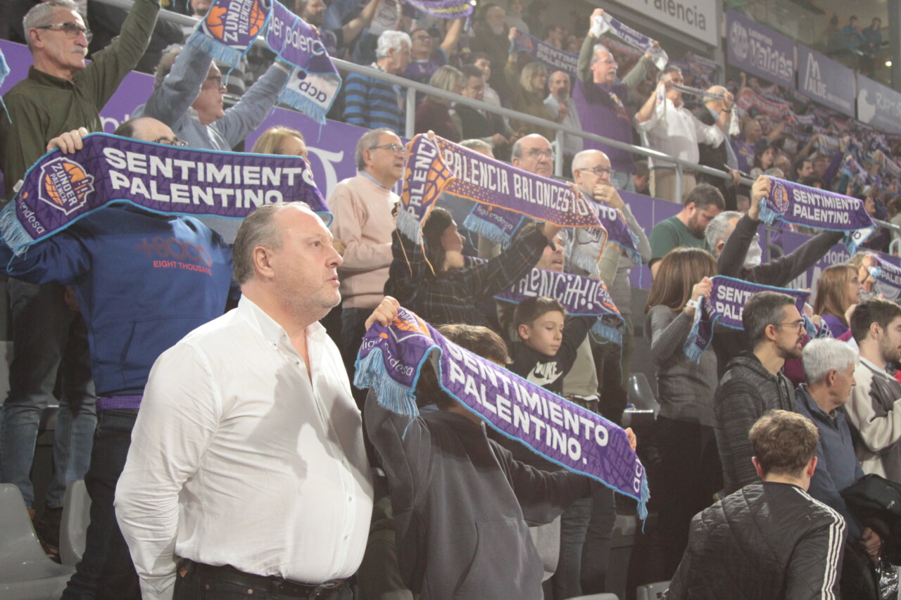 Aficionados animando con bufandas en un partido de baloncesto