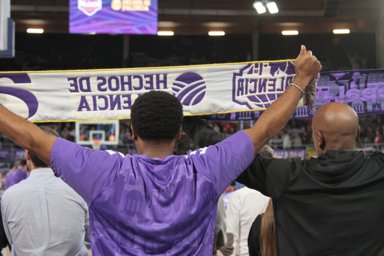 Aficionados sosteniendo una bufanda en un partido de baloncesto