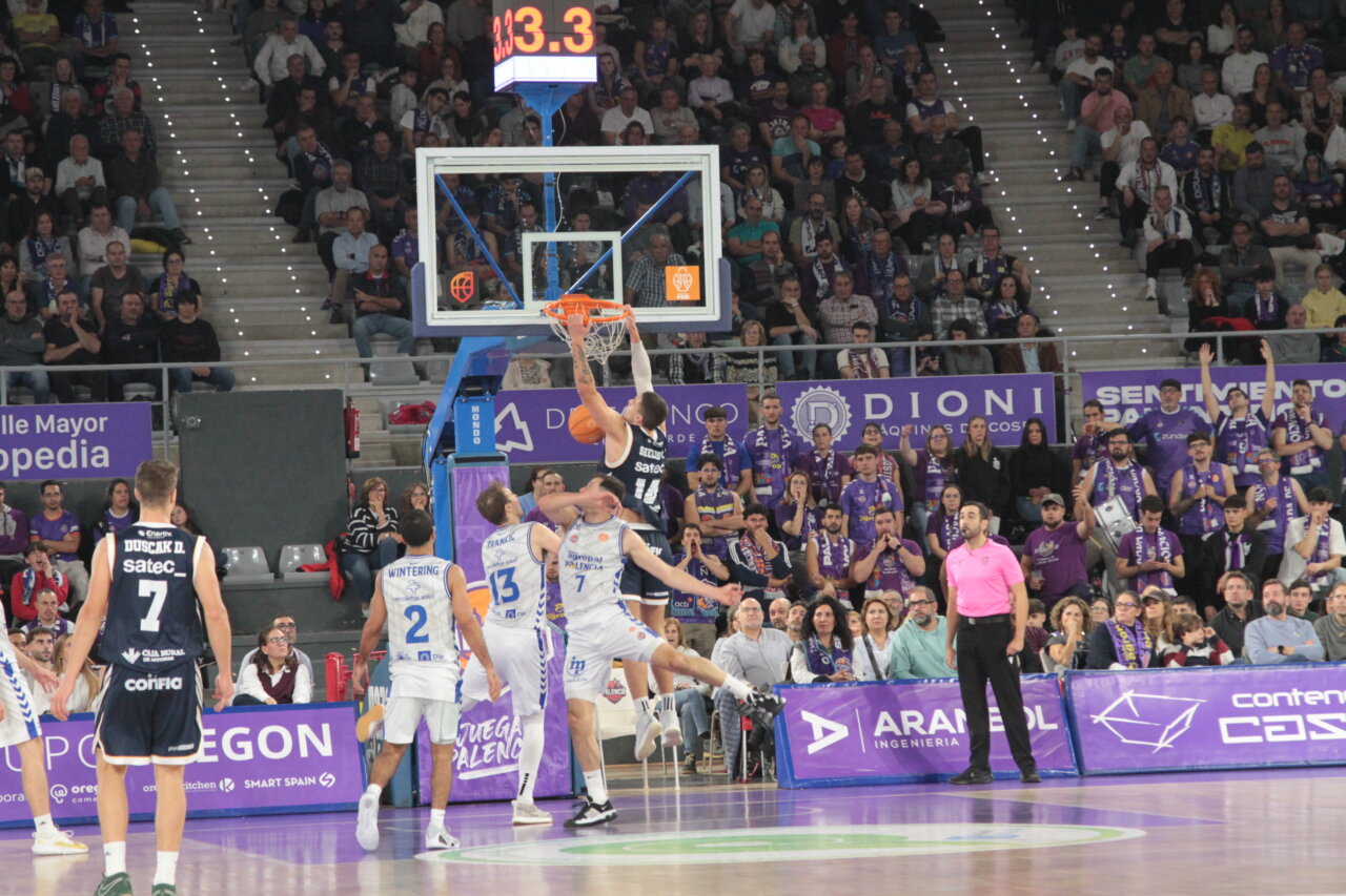 Jugadores de baloncesto en acción durante un partido entre Palencia y Oviedo.
