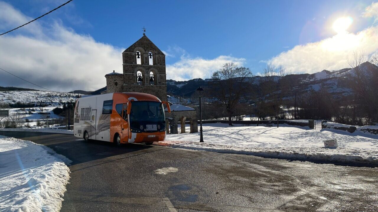 Bibliobús en un paisaje nevado con una iglesia al fondo
