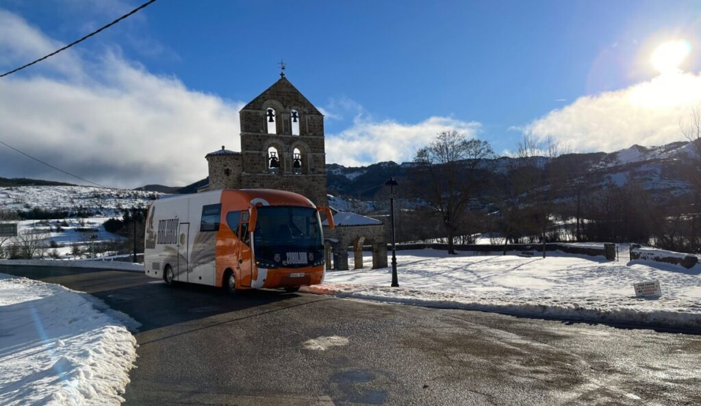 Bibliobús en un paisaje nevado con una iglesia al fondo