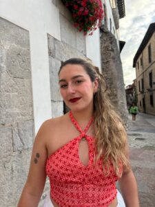 Joven mujer con blusa roja sonriente en una calle de piedra