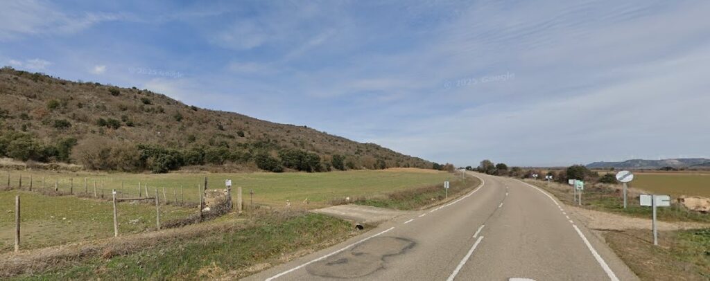 Carretera P-412 en la comarca del Cerrato, Palencia, con vegetación y montañas.