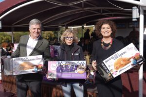 Tres personas sosteniendo cajas de pavo asado Cascajares en un evento