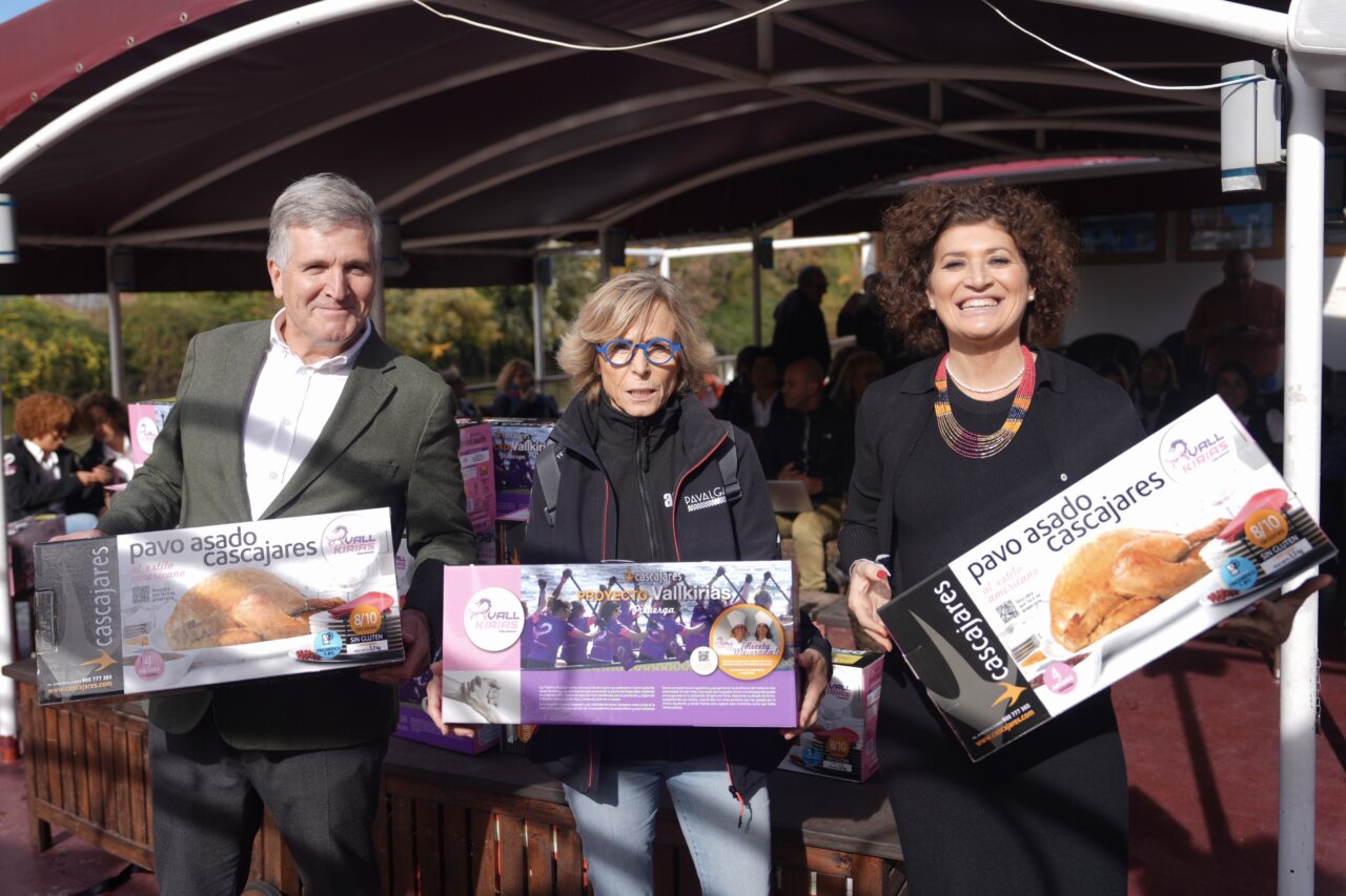 Tres personas sosteniendo cajas de pavo asado Cascajares en un evento
